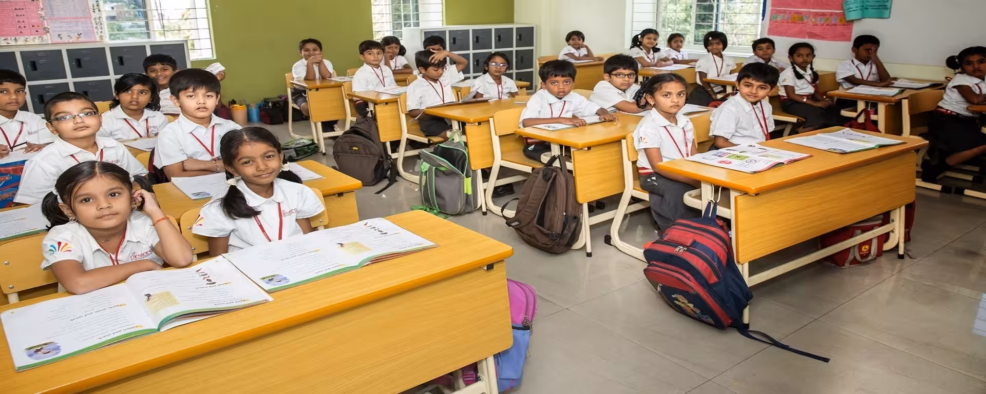 School desks with bags hanging on the sides in a classroom setting